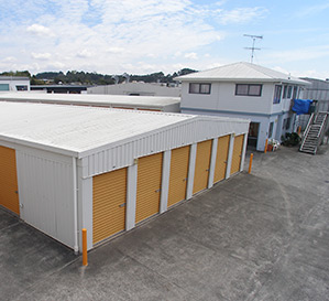 Drive-up storage units with orange roller doors and the site office at Sisac Storage, Silverdale